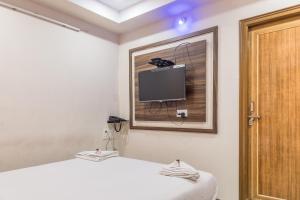 a bedroom with a bed and a tv on the wall at Hotel Renuka in Visakhapatnam