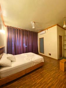 ein Schlafzimmer mit einem Bett und einem lila Vorhang in der Unterkunft Bougainvillea Inn - Maldives in Fulidhoo