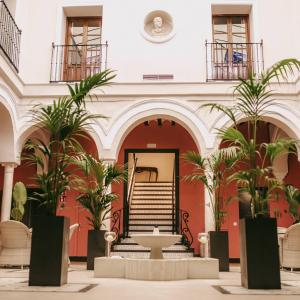 ein Gebäude mit einer Treppe und Palmen in der Unterkunft Palacio San Fernando in Utrera