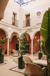 eine Lobby eines Gebäudes mit Stühlen und Pflanzen in der Unterkunft Palacio San Fernando in Utrera