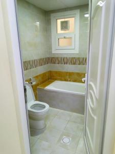 a bathroom with a toilet and a bath tub at Al Rawda Apartments -Ajman in Ajman 