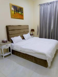 a bedroom with a large bed with white sheets at Al Rawda Apartments -Ajman in Ajman 