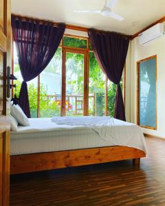 a bedroom with a bed and a large window at Bougainvillea Inn - Maldives in Fulidhoo