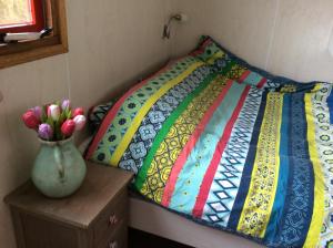 a bed with a colorful quilt and a vase of flowers at Repelsteeltje op Terschelling in Formerum
