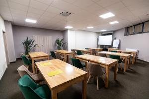 une salle de classe vide avec des tables en bois et des chaises vertes dans l'établissement GRAND VIEW Hotel & Suites Copou, à Iaşi