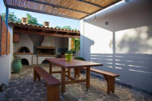a patio with a wooden table and benches and a fireplace at Villa Mary in Kefallonia