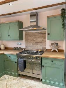 a kitchen with green cabinets and a stove at Ferry Lane Cottage in Kings Lynn