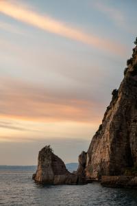 a rock formation in the water with a sunset at La Casa del Verricello - Sea view house in Meta