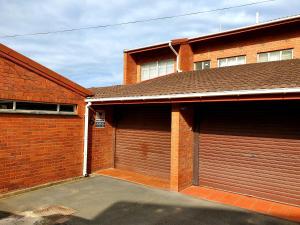 two garage doors on a brick building with a driveway at Dolphin View Self Catering in Scottburgh