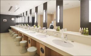 a large bathroom with a row of sinks and toilets at First Cabin Kansai Airport in Izumi-Sano