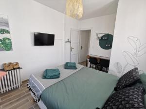 um quarto com uma cama e uma televisão de ecrã plano em Les Rauches - Quai Loire - Chambre Jungle em Châteauneuf-sur-Loire