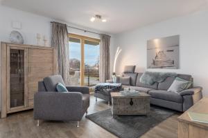 a living room with a couch and chairs and a table at Villa Sanddorn - Ferienwohnungen in Börgerende-Rethwisch