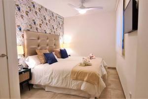 a bedroom with a large white bed with blue pillows at LUJOSO APARTAMENTO NUEVO PLAYA CENTRO in Estepona +19 photos