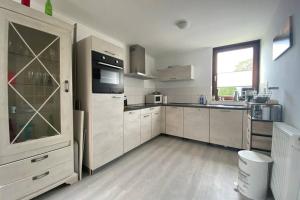 a large kitchen with white cabinets and a window at Traumhaftes geräumiges Ferienhaus in Meernähe in Bruinisse