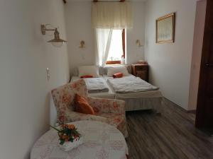 a room with two beds and a chair and a window at Míves Vendégház in Pogány