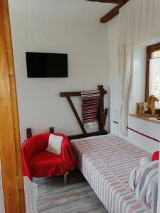 um quarto com uma cama e uma cadeira vermelha em Míves Vendégház em Pogány