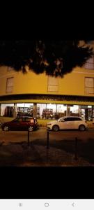 two cars parked in a parking lot in front of a building at Guest House Pacifica in Quarteira