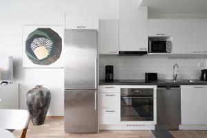 uma cozinha com armários brancos e um frigorífico de aço inoxidável em Premier Residences Helsinki em Helsinque