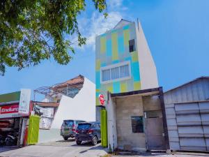 a multicolored building with cars parked in a parking lot at Super OYO Capital O 90336 Olive Guest House in Surabaya