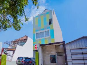 kolorowy budynek z samochodami zaparkowanymi przed nim w obiekcie Super OYO Capital O 90336 Olive Guest House w mieście Surabaja