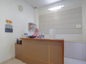 a woman sitting at a counter in a room at Super OYO Capital O 90336 Olive Guest House in Surabaya