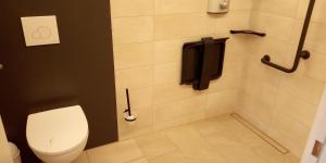 a bathroom with a toilet and a phone on the wall at Le Baugyte - Gite d'ETAPE - 15 lits in Baugy