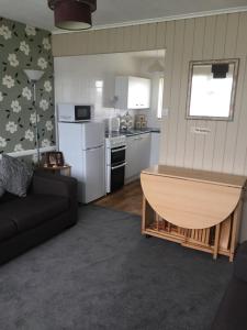 een woonkamer met een bank en een keuken bij 2 bed dog friendly chalet on sunbeach Scratby in Great Yarmouth +5 foto's
