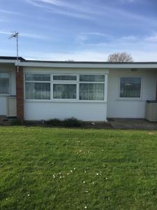 een wit huis met een groen gazon ervoor bij 2 bed dog friendly chalet on sunbeach Scratby in Great Yarmouth