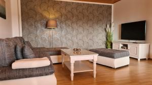 WilhelmsthalにあるModerne Ferienwohnung mit eigenem Garten und traumhaften Blickのソファとテーブルのあるリビングルーム