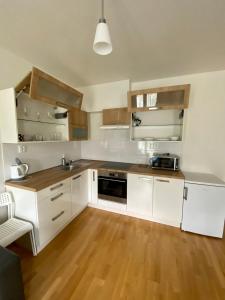 a kitchen with white cabinets and a wooden floor at Apartment David Garden Towers in Prague