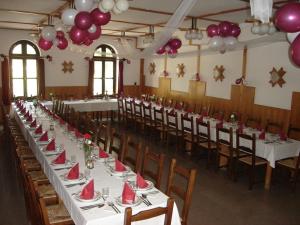 ケルメンドにあるHalászcsárda-Panzióの長いテーブルと赤いナプキンと風船が並ぶ宴会場