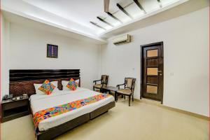 新德里的住宿－FabHotel Exotica Greenpark，卧室配有一张床、一张桌子和椅子