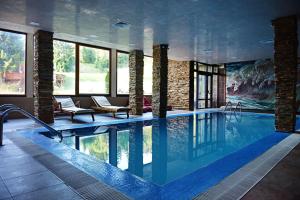 a pool in a hotel with chairs and a swimming pool at Forest Nook Aparthotel in Pamporovo