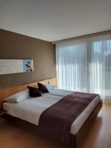 un grande letto in una camera da letto con una grande finestra di Hotel & Restaurant STERNEN MURI bei Bern a Berna Altre 35 foto
