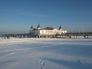 a building on the beach with footprints in the snow at Apartmenthaus Aurum in Ahlbeck