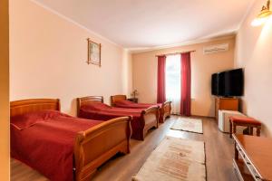 a row of beds in a room with a tv at Hotel Denis in Daneş