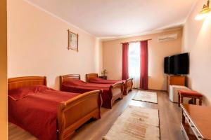 szereg łóżek w pokoju z telewizorem w obiekcie Hotel Denis w mieście Daneş