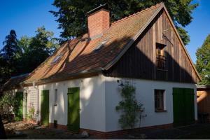 a white house with a brown roof and green doors at Heuboden in Mellenthin
