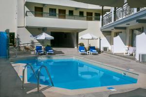 a swimming pool in front of a hotel with chairs and umbrellas at Crystallo Apartments in Paphos