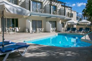 a pool with a chair and an umbrella next to a house at Crystallo Apartments in Paphos