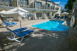 a swimming pool with two chairs and an umbrella and an umbrella at Crystallo Apartments in Paphos