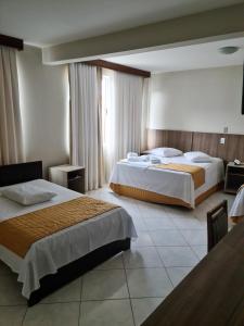 um quarto de hotel com duas camas e uma janela em San Marino Palace Hotel em Guarapuava