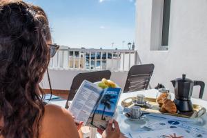 una mujer sentada en una mesa leyendo un libro en Rincon Marinero with large terrace and views, en Arrecife