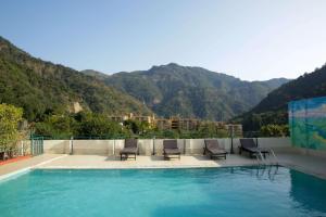 a swimming pool with chairs and mountains in the background at Hotel Dewa Retreat- A Himalayan Boutique Hotel in Rishīkesh