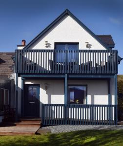 a house with a balcony with two chairs on it at Rowan Cottage Self Catering in Portree