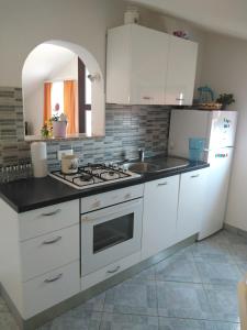 a kitchen with white cabinets and a stove top oven at Apartments Nina in Ravni
