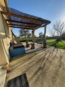 a wooden pergola on the side of a house at la longère charmante in Céaux