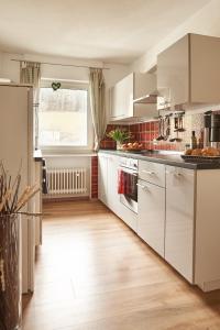 a kitchen with white cabinets and a wooden floor at Ferienhaus Willkommen in Winterberg