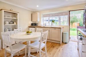 a kitchen with a white table and white chairs at Situated in Stunning Highleigh Village,'BRAMLEY FALL COTTAGE'-Attached Cottage,3 Bedrooms-1 on ground level, SLEEPS 6-2 Bathrooms, 9 mins to Sandy Wittering Beach, 5 mins from Southend Barns, Child friendly,Small Breed Dog Friendly 2 max, Parking-EV Point in Chichester