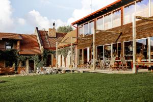 une maison dotée d'une terrasse couverte avec des chaises et une pelouse dans l'établissement Vēju Paradīze, à Pāvilosta